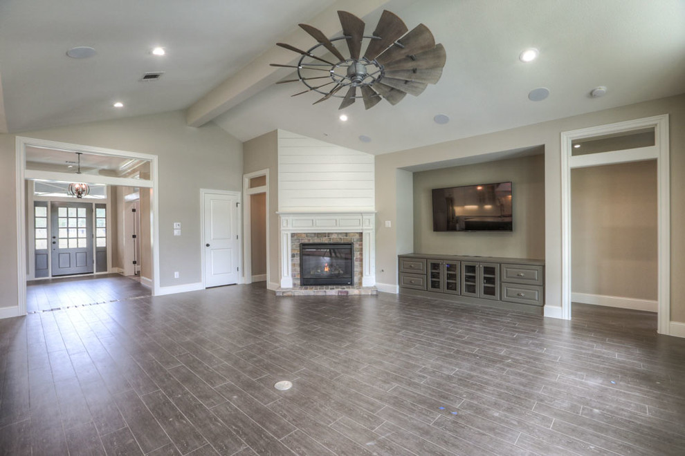 This is an example of a mid-sized transitional formal open concept living room in Houston with beige walls, dark hardwood floors, a corner fireplace, a stone fireplace surround, a wall-mounted tv and brown floor.