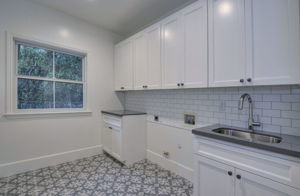 Photo of a mid-sized mediterranean laundry room in San Francisco with shaker cabinets, white cabinets, quartz benchtops, an undermount sink, ceramic floors, grey floor and grey benchtop.