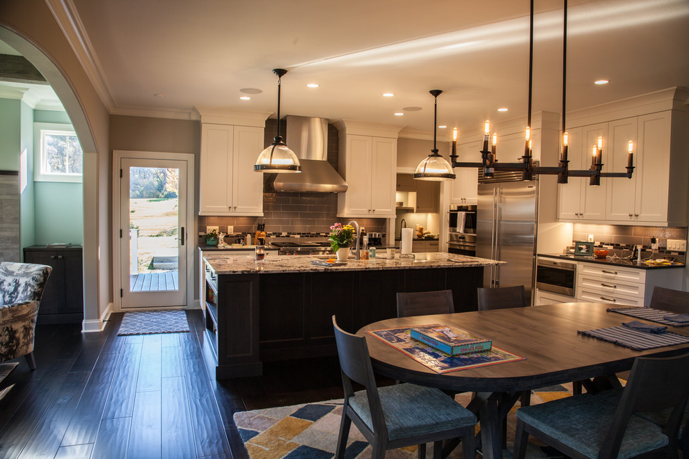Inspiration for a transitional dark wood floor and brown floor open concept kitchen remodel with an undermount sink, shaker cabinets, white cabinets, granite countertops, beige backsplash, subway tile backsplash, stainless steel appliances and an island