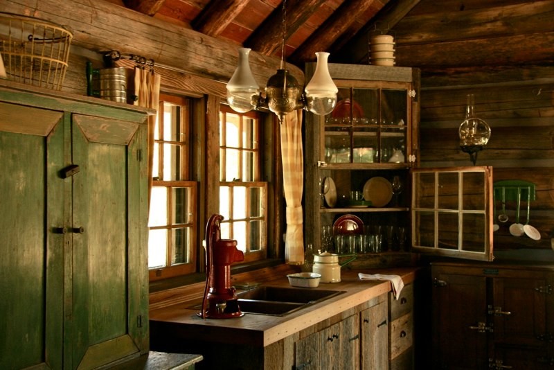 Mid-sized mountain style u-shaped gray floor eat-in kitchen photo with a double-bowl sink, glass-front cabinets, distressed cabinets, wood countertops, brown backsplash, wood backsplash, black appliances, no island and brown countertops