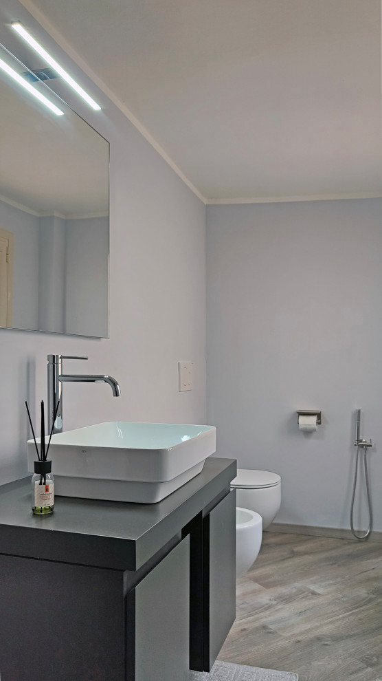 Пример оригинального дизайна: маленький туалет в стиле модернизм с плоскими фасадами, серыми фасадами, инсталляцией, серыми стенами, полом из ламината, настольной раковиной, столешницей из ламината, серым полом, серой столешницей и подвесной тумбой для на участке и в саду