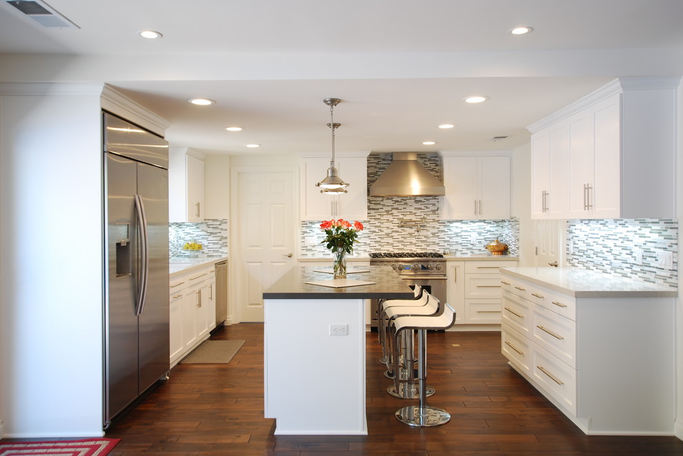 Mid-sized contemporary u-shaped eat-in kitchen in Los Angeles with shaker cabinets, white cabinets, multi-coloured splashback, matchstick tile splashback, stainless steel appliances, dark hardwood floors, with island and quartzite benchtops.
