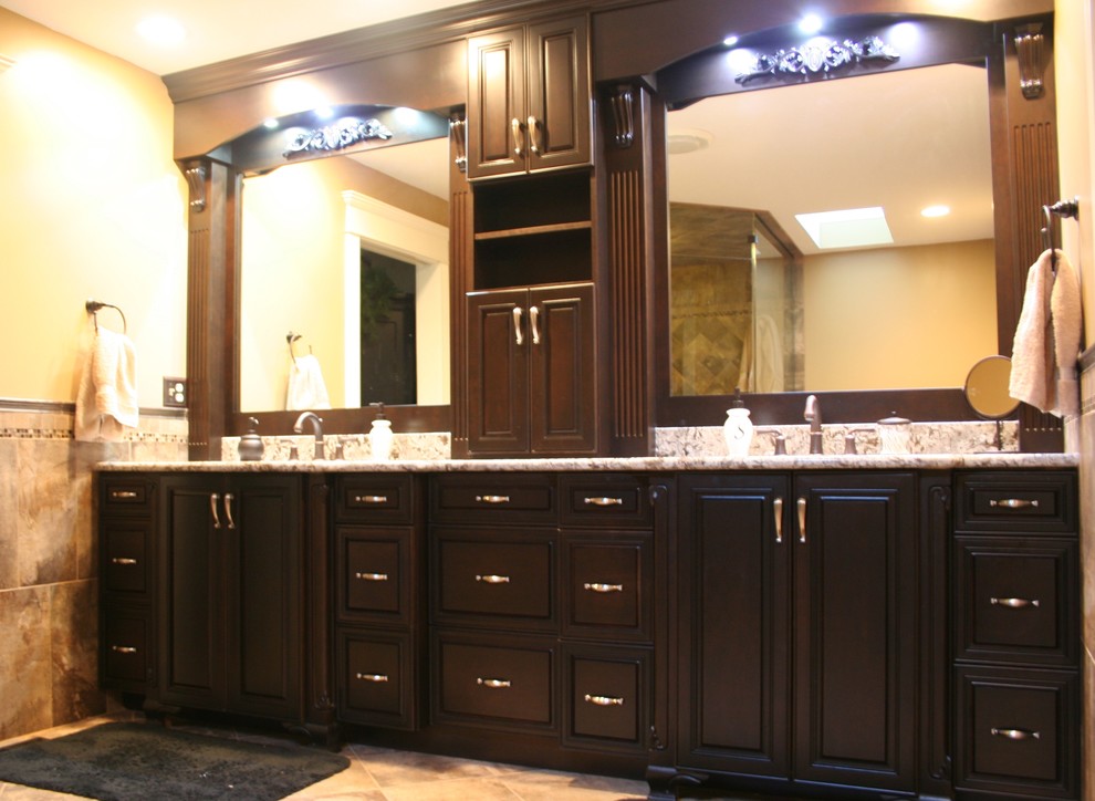 This is an example of an expansive traditional master bathroom in Other with an undermount sink, raised-panel cabinets, dark wood cabinets, granite benchtops, beige walls and porcelain floors.