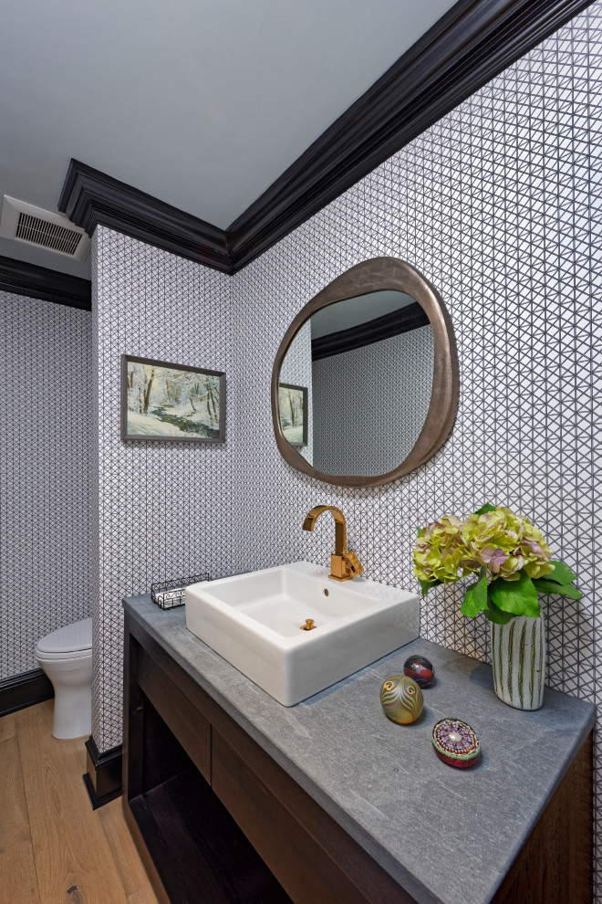 Inspiration for a small contemporary cloakroom in DC Metro with flat-panel cabinets, dark wood cabinets, a one-piece toilet, light hardwood flooring, a vessel sink, granite worktops, brown floors, grey worktops, a built in vanity unit and wallpapered walls.