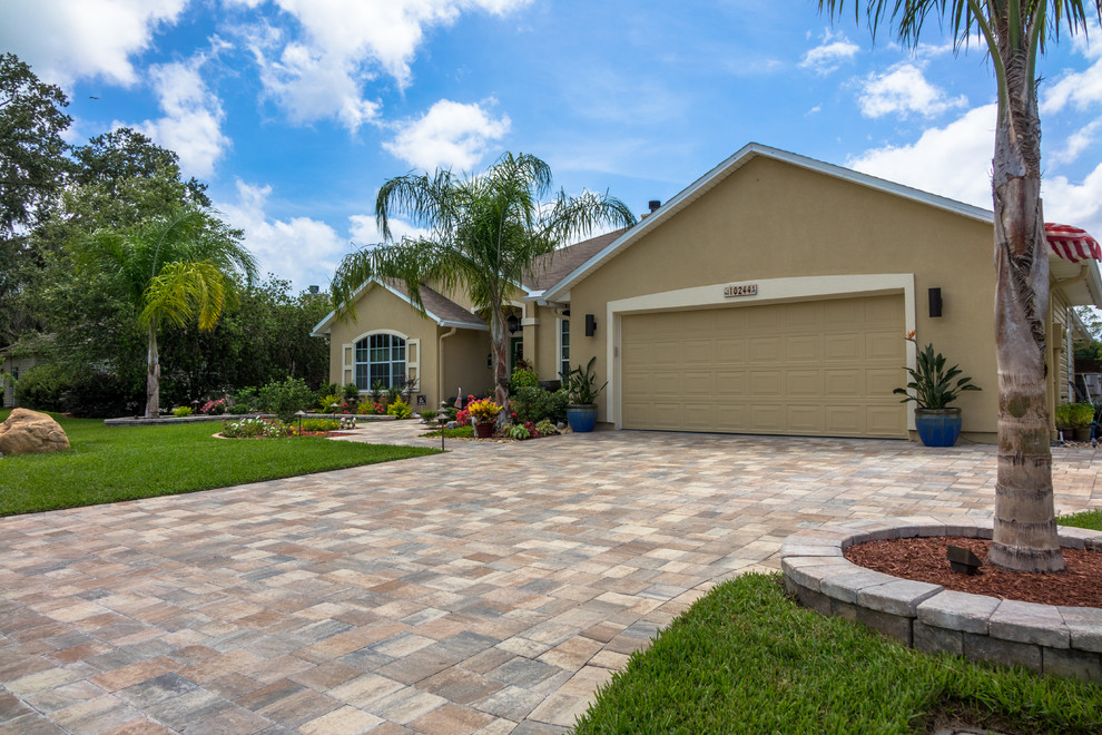 Design ideas for an expansive traditional front yard full sun driveway for summer in Jacksonville with a retaining wall and natural stone pavers.