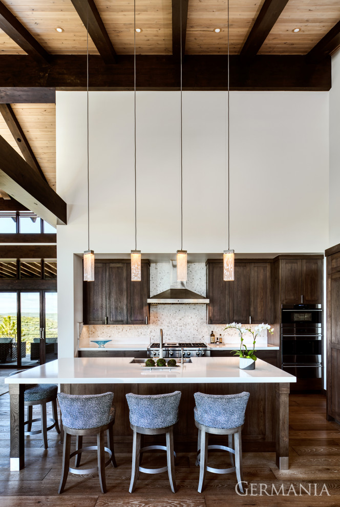 Photo of a modern single-wall open plan kitchen in Salt Lake City with a drop-in sink, shaker cabinets, dark wood cabinets, white splashback, black appliances, medium hardwood floors, with island, white benchtop and wood.