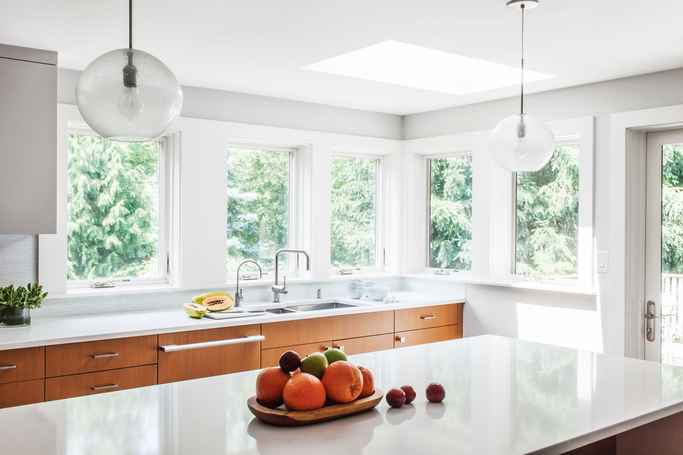 Example of a minimalist u-shaped eat-in kitchen design in Boston with an undermount sink, flat-panel cabinets, medium tone wood cabinets, blue backsplash, glass tile backsplash and paneled appliances