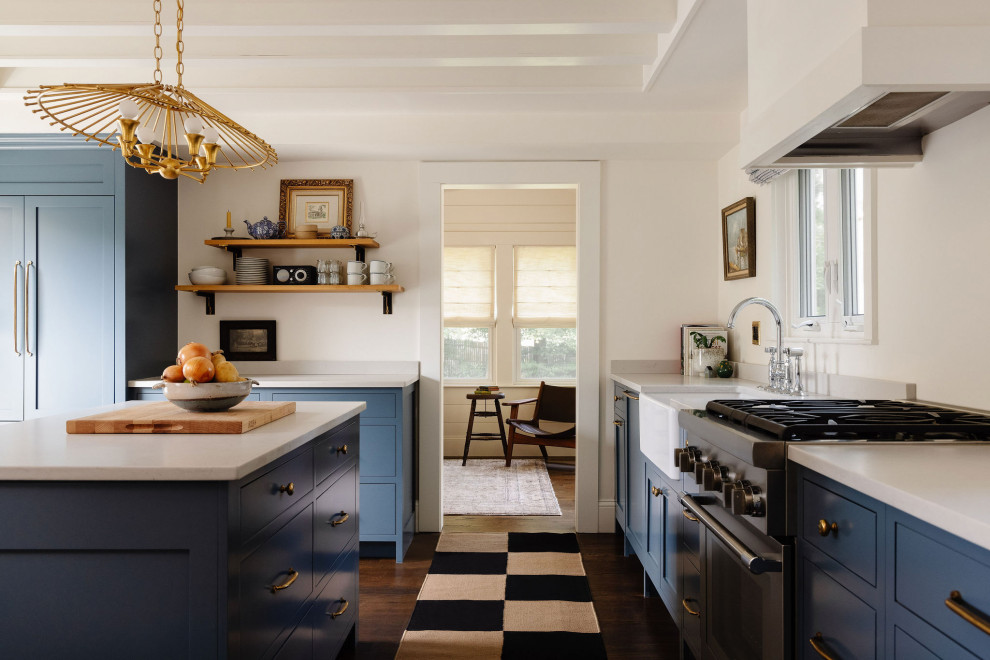 Transitional u-shaped dark wood floor, brown floor and exposed beam enclosed kitchen photo in Boston with a farmhouse sink, shaker cabinets, blue cabinets, stainless steel appliances, an island and white countertops