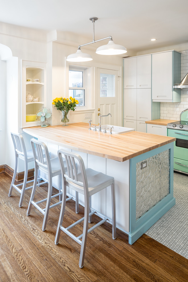 Photo of a small transitional l-shaped eat-in kitchen in Toronto with a farmhouse sink, flat-panel cabinets, white cabinets, wood benchtops, white splashback, subway tile splashback, coloured appliances, marble floors and a peninsula.