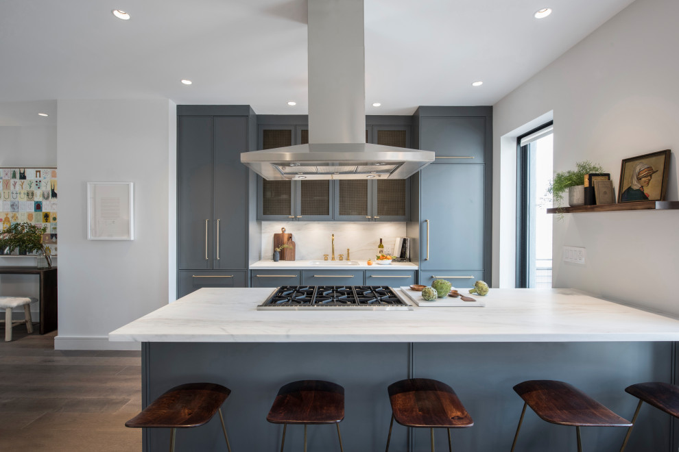 Photo of a large contemporary galley kitchen in New York with stone slab splashback, with island, flat-panel cabinets, grey cabinets, white splashback, stainless steel appliances, medium hardwood floors, grey floor and white benchtop.