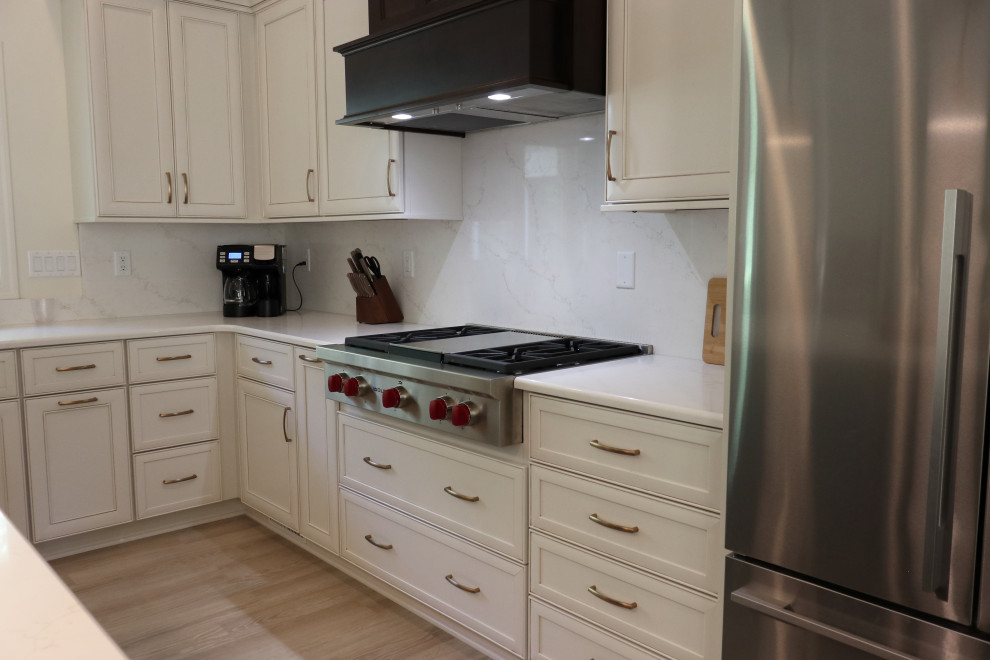 Large transitional l-shaped kitchen photo with an undermount sink, recessed-panel cabinets, quartz countertops, white backsplash, quartz backsplash, stainless steel appliances and white countertops
