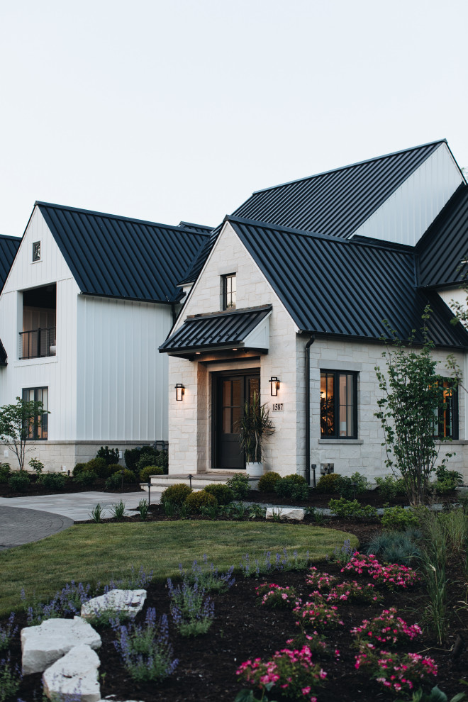 Aménagement d'une grande façade de maison blanche classique avec un toit noir.