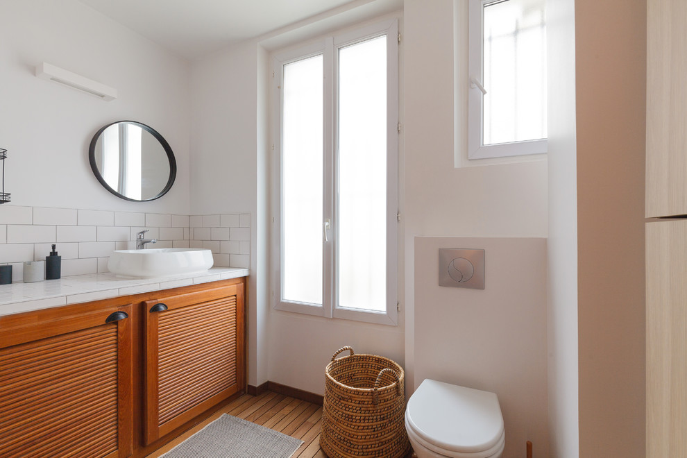 Design ideas for a mid-sized eclectic master bathroom in Paris with white walls, dark hardwood floors, brown floor, a curbless shower, a wall-mount toilet, white tile, ceramic tile, a console sink, tile benchtops and white benchtops.