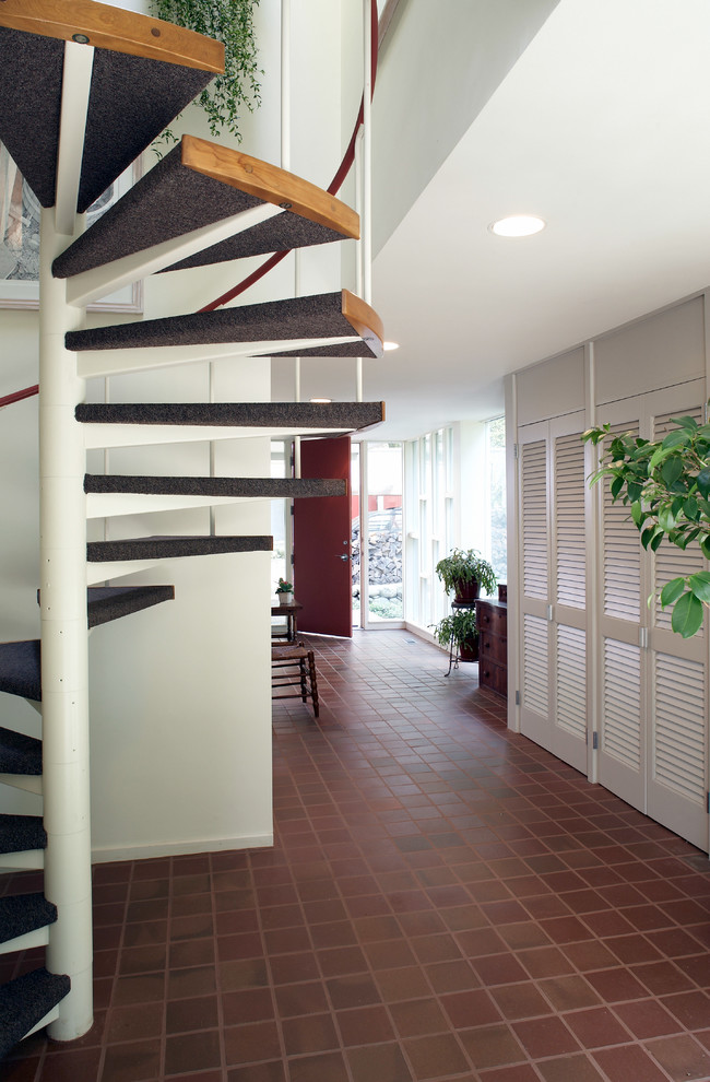 Midcentury hallway in Boston with white walls and terra-cotta floors.