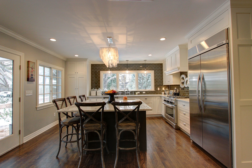 Inspiration for a large transitional l-shaped dark wood floor enclosed kitchen remodel in Denver with an undermount sink, shaker cabinets, white cabinets, marble countertops, brown backsplash, subway tile backsplash, stainless steel appliances and an island