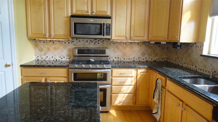 Inspiration for a transitional light wood floor kitchen remodel in St Louis with a double-bowl sink, light wood cabinets, granite countertops, multicolored backsplash and stainless steel appliances
