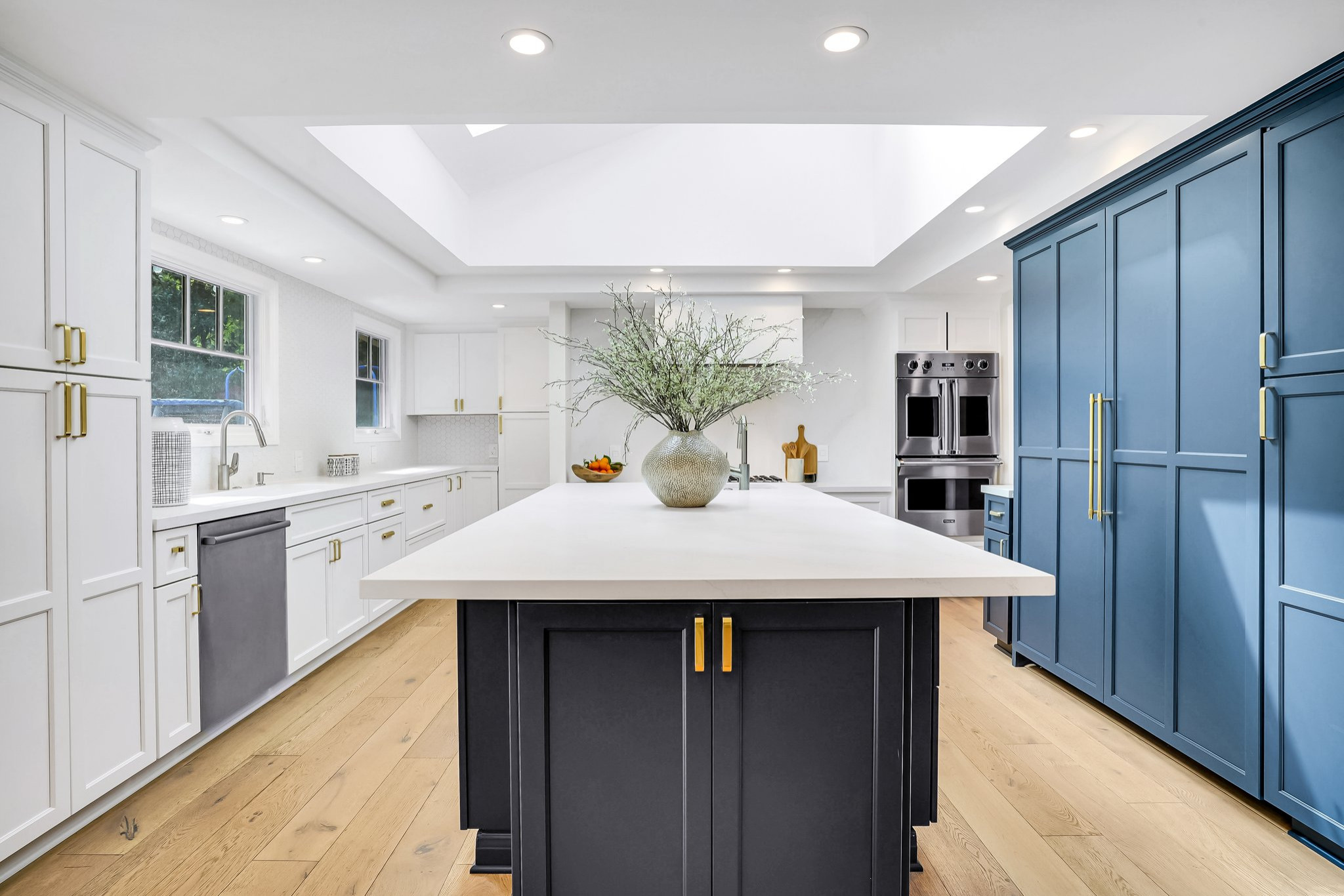 Example of a transitional u-shaped light wood floor and beige floor kitchen design in San Francisco with recessed-panel cabinets, white cabinets, white backsplash, stainless steel appliances, an islan