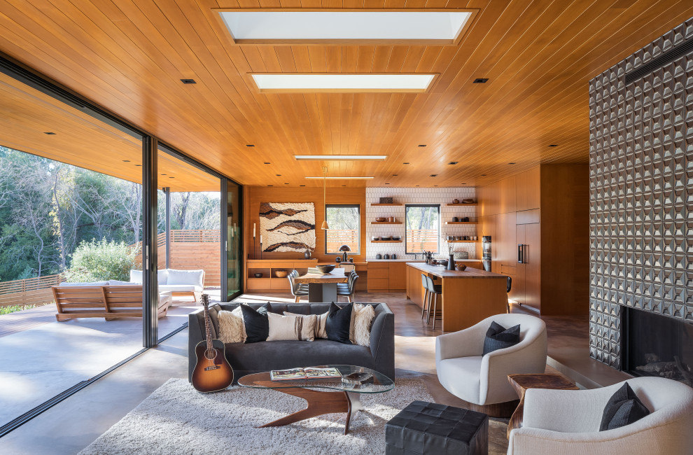 Mid-sized midcentury open concept living room in San Francisco with concrete floors, a two-sided fireplace, a tile fireplace surround, grey floor, wood and wood walls.