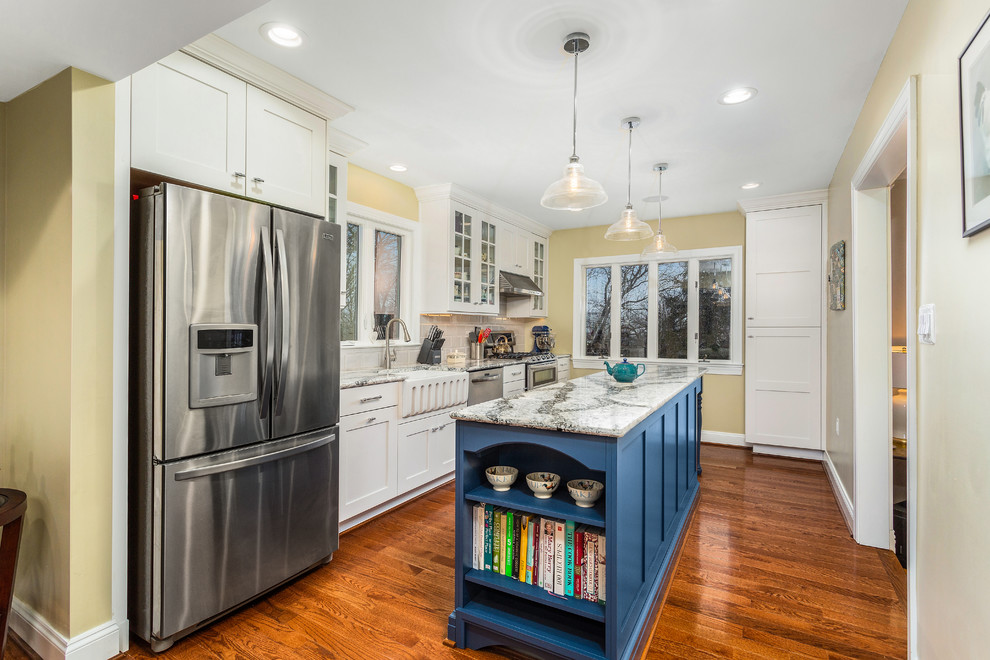 Design ideas for a traditional single-wall kitchen in DC Metro with shaker cabinets, white cabinets, grey splashback, stainless steel appliances, medium hardwood floors, with island, brown floor and grey benchtop.