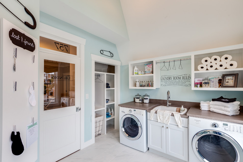This is an example of a beach style utility room in Other with a drop-in sink, shaker cabinets, white cabinets, wood benchtops, blue walls, a side-by-side washer and dryer and brown benchtop.