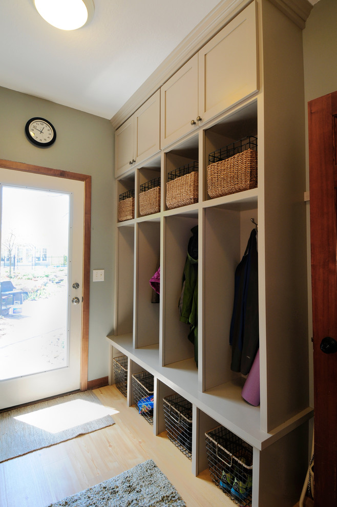 Photo of a mid-sized traditional single-wall utility room in Minneapolis with an undermount sink, shaker cabinets, grey cabinets, granite benchtops, light hardwood floors, a stacked washer and dryer and grey walls.