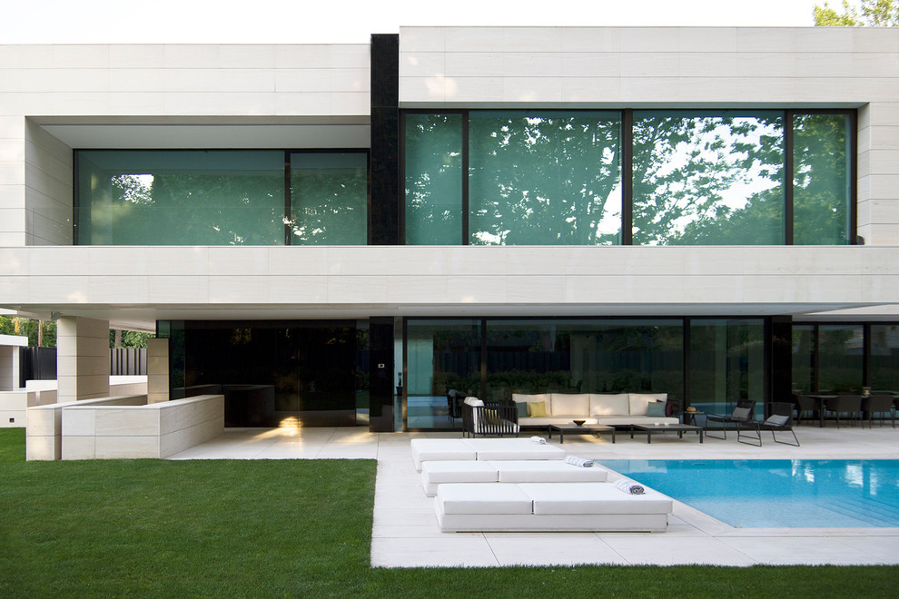 This is an example of a large modern two-storey white exterior in Madrid with a flat roof and stone veneer.