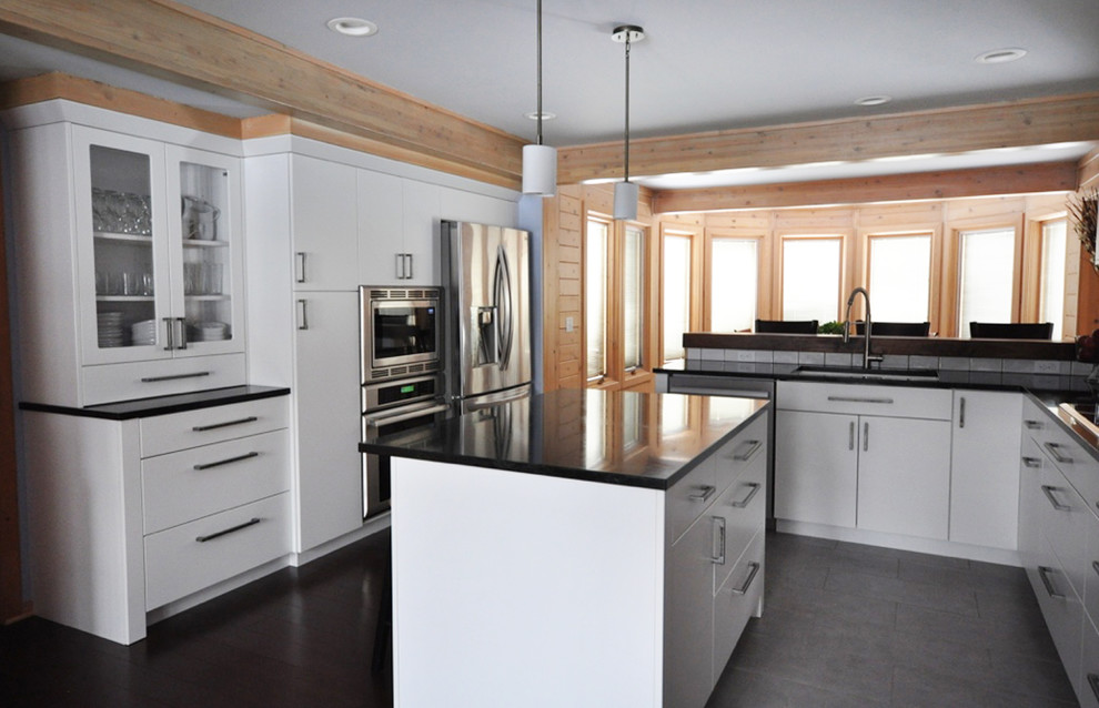 Inspiration for a mid-sized transitional l-shaped dark wood floor eat-in kitchen remodel in Grand Rapids with an undermount sink, flat-panel cabinets, white cabinets, soapstone countertops, white backsplash, subway tile backsplash, stainless steel appliances and an island