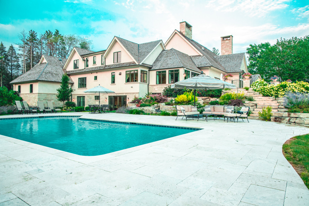 Example of a large mountain style backyard stone and rectangular pool landscaping design in Chicago