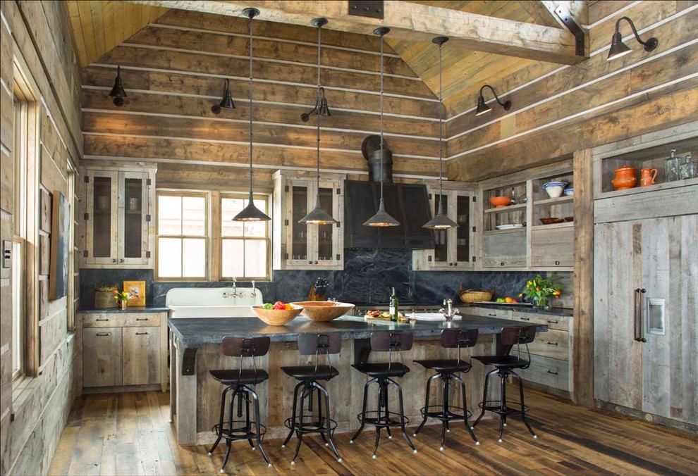 Example of a mountain style dark wood floor kitchen design in Denver with a farmhouse sink, flat-panel cabinets, white cabinets, black backsplash, stone slab backsplash, an island and paneled appliances