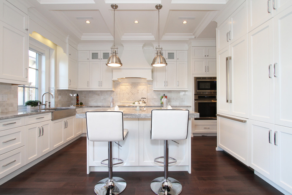 Mid-sized transitional l-shaped dark wood floor eat-in kitchen photo in Vancouver with a farmhouse sink, shaker cabinets, white cabinets, gray backsplash, stainless steel appliances, an island, granite countertops and stone tile backsplash