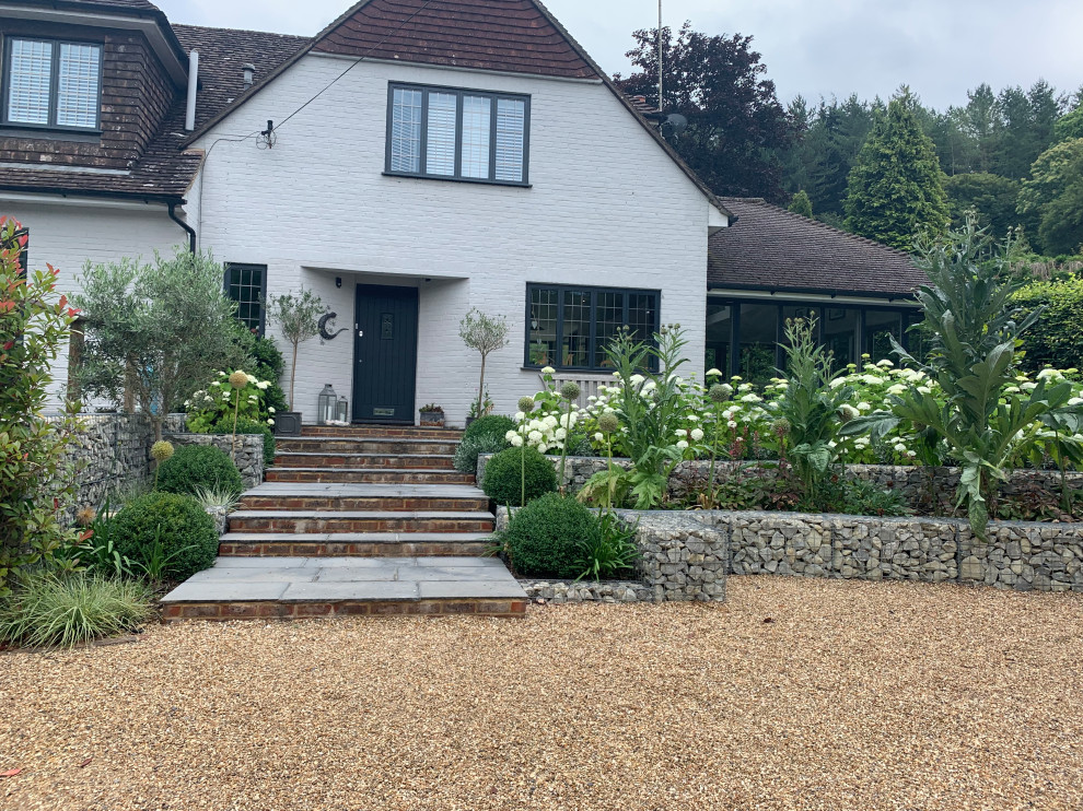 Large country front yard driveway in Surrey with with flowerbed and river rock.