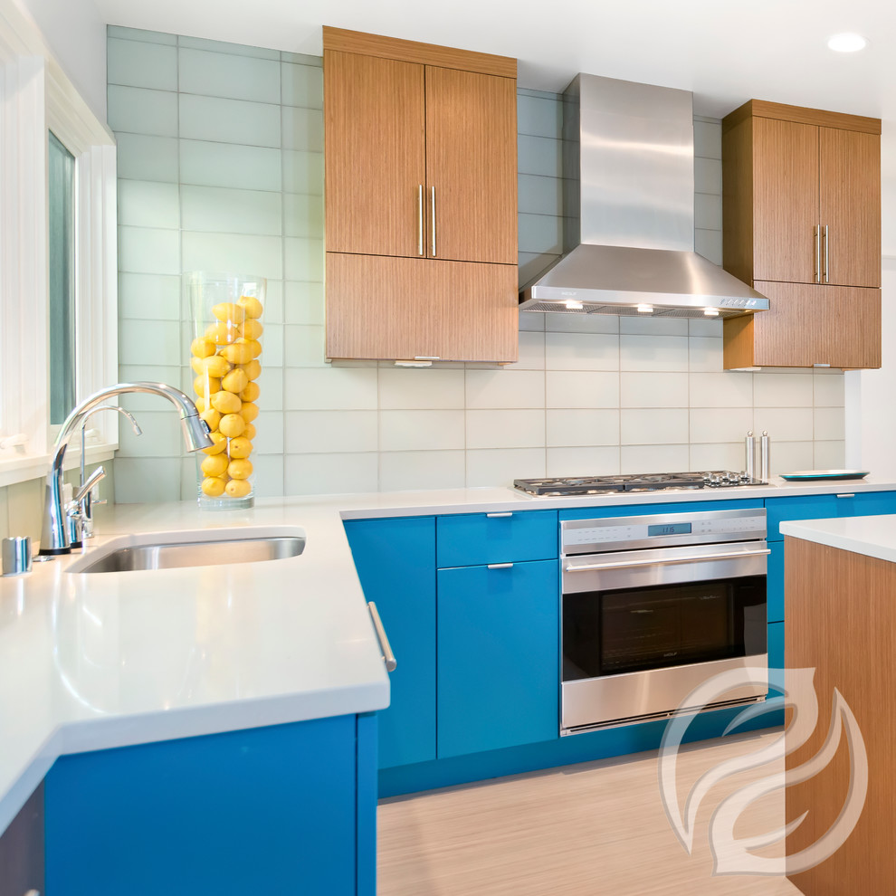 Inspiration for an eclectic u-shaped light wood floor kitchen remodel in Milwaukee with flat-panel cabinets, turquoise cabinets, stainless steel appliances, an island and white countertops