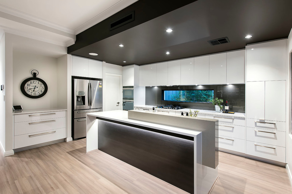 Photo of a large contemporary galley open plan kitchen in Perth with flat-panel cabinets, white cabinets, quartz benchtops, black splashback, window splashback, stainless steel appliances, light hardwood floors, multiple islands, brown floor and white benchtop.