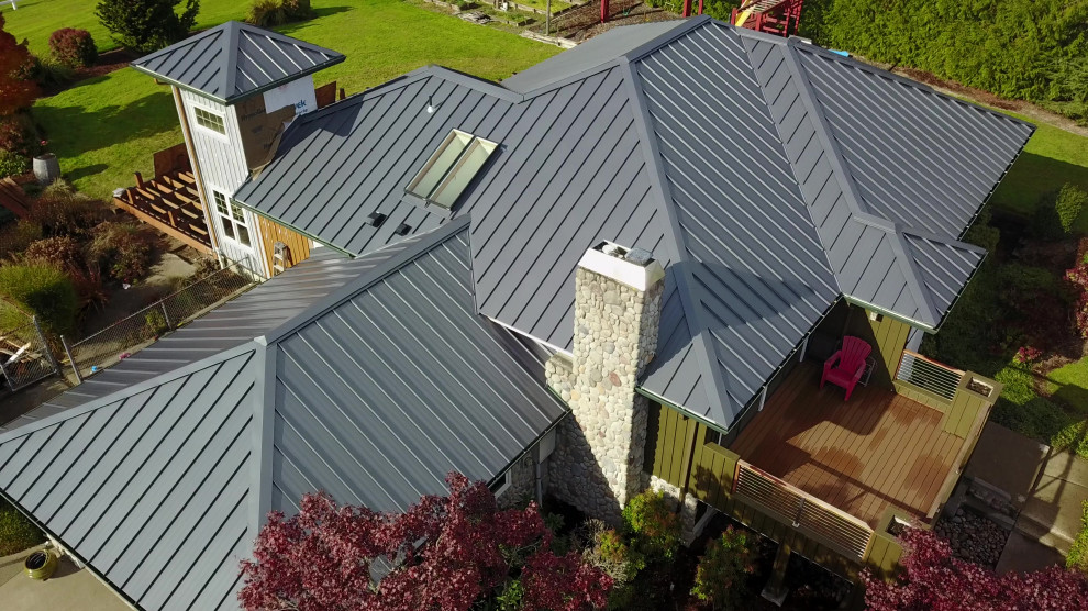 Cette photo montre une grande façade de maison multicolore tendance en planches et couvre-joints de plain-pied avec un revêtement mixte, un toit à quatre pans, un toit en métal et un toit gris.