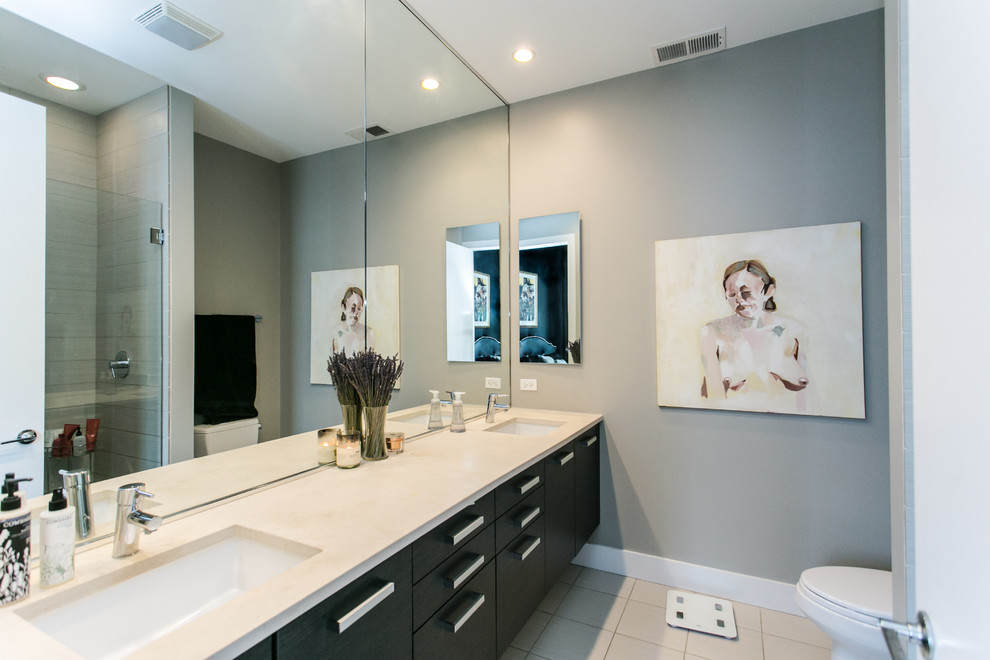 This is an example of a mid-sized contemporary 3/4 wet room bathroom in Chicago with flat-panel cabinets, black cabinets, a one-piece toilet, white tile, ceramic tile, beige walls, ceramic floors, an undermount sink, engineered quartz benchtops, white floor and a hinged shower door.