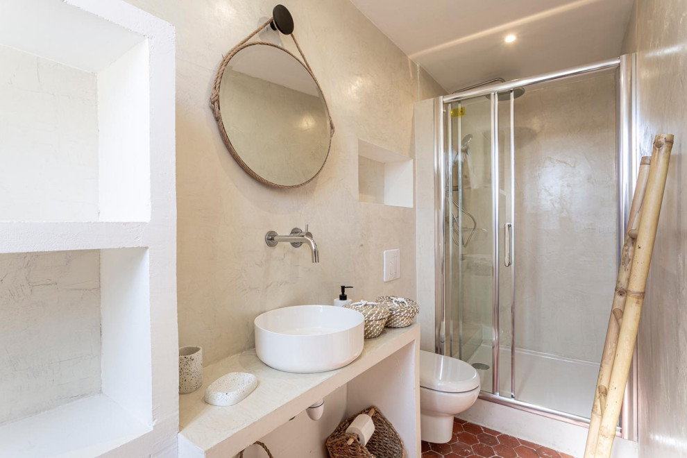 Inspiration for a mid-sized eclectic bathroom in Other with open cabinets, a one-piece toilet, beige walls, terra-cotta floors, a drop-in sink, red floor, a sliding shower screen and beige benchtops.