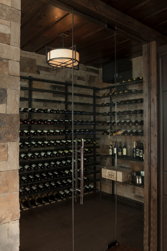 This is an example of a large contemporary wine cellar in Denver with dark hardwood floors, storage racks and grey floor.