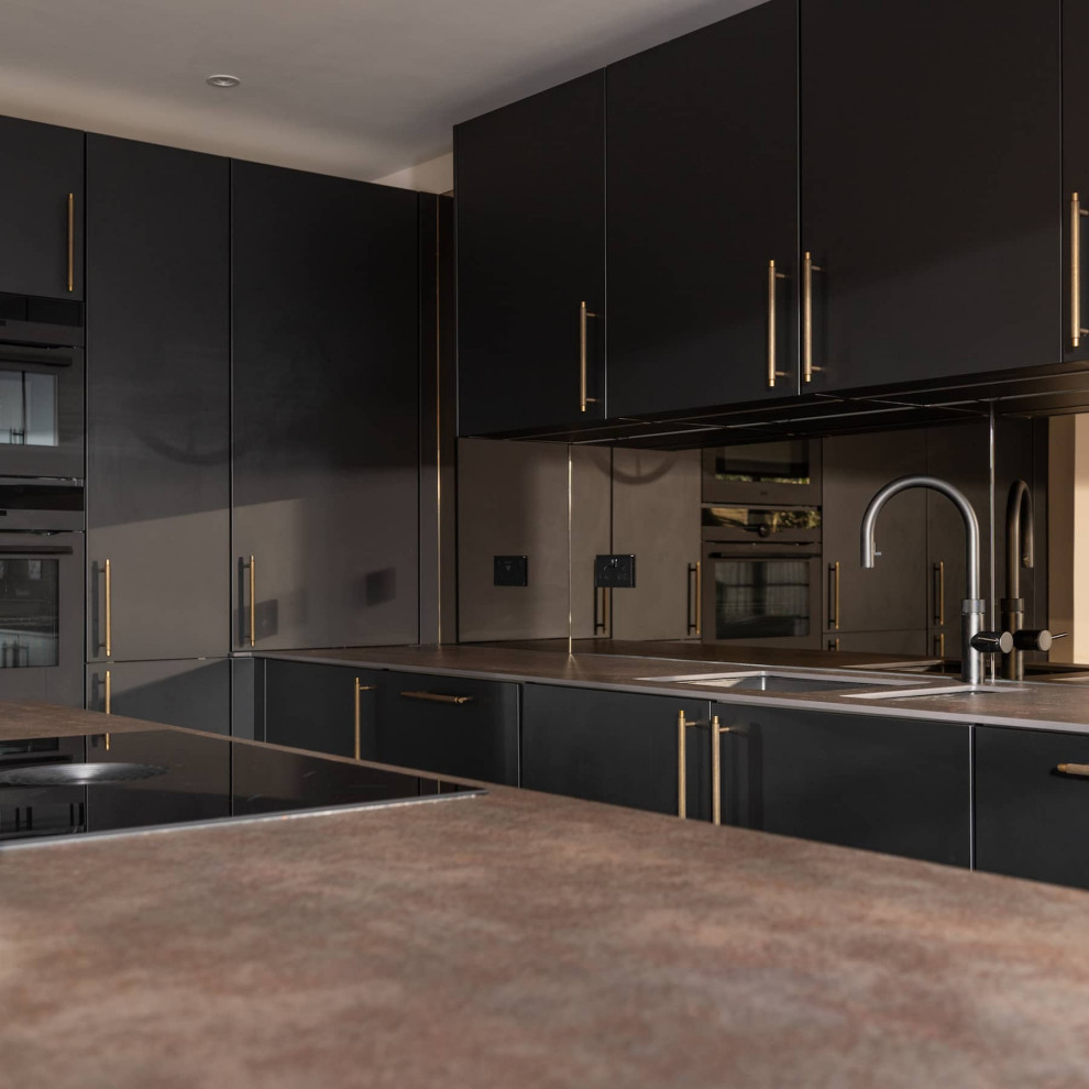 This is an example of a mid-sized modern l-shaped open plan kitchen in Hertfordshire with an undermount sink, flat-panel cabinets, black cabinets, quartzite benchtops, brown splashback, glass sheet splashback, black appliances, light hardwood floors, with island, brown floor, brown benchtop and coffered.