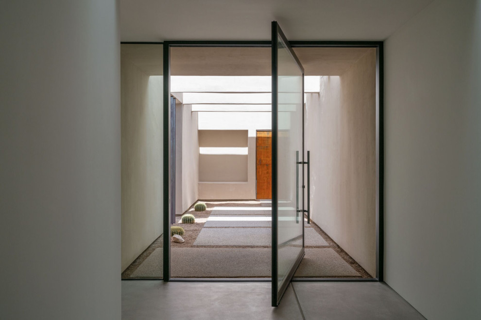 Стильный дизайн: вестибюль в стиле модернизм с бетонным полом, поворотной входной дверью, стеклянной входной дверью и серым полом - последний тренд