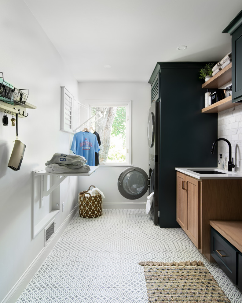 Mid-sized transitional single-wall dedicated laundry room in Kansas City with an undermount sink, recessed-panel cabinets, green cabinets, quartz benchtops, white splashback, marble splashback, white walls, porcelain floors, a stacked washer and dryer, white floor and white benchtop.