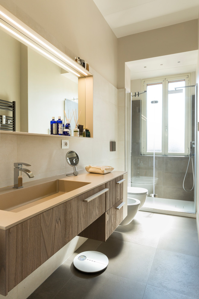 Mid-sized transitional 3/4 bathroom in Rome with flat-panel cabinets, medium wood cabinets, an alcove shower, a bidet, beige walls, ceramic floors, an integrated sink, grey floor and a hinged shower door.