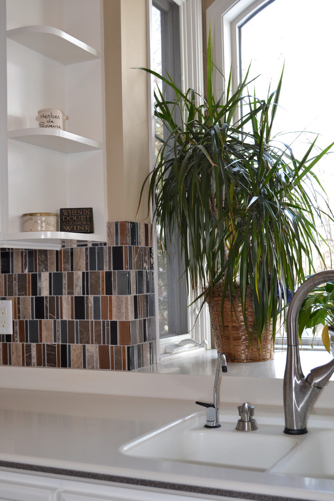 Example of a mid-sized transitional kitchen design with an integrated sink, raised-panel cabinets, multicolored backsplash and glass tile backsplash