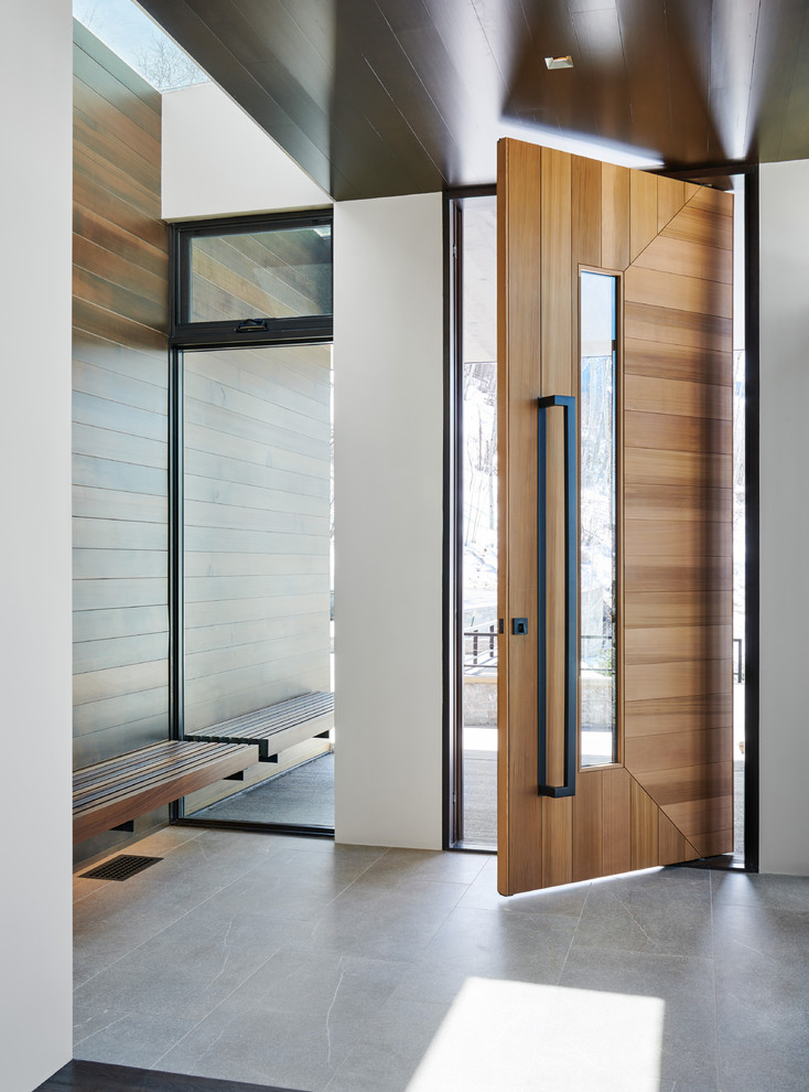 Photo of a large contemporary front door in Denver with white walls, porcelain floors, a pivot front door, a medium wood front door and grey floor.