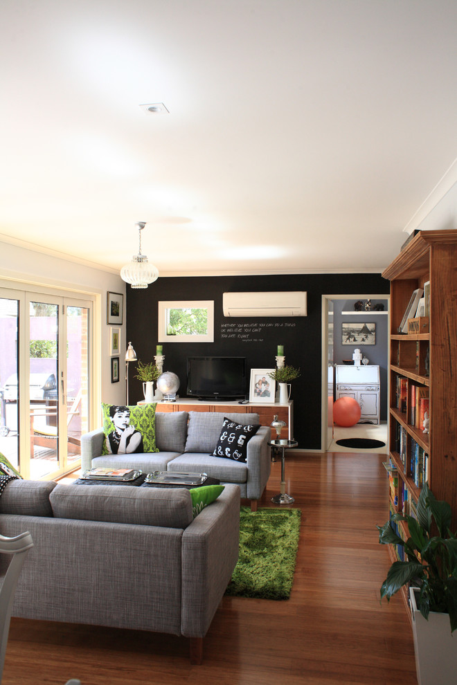 Mid-sized transitional open concept family room in Melbourne with black walls, bamboo floors and a freestanding tv.