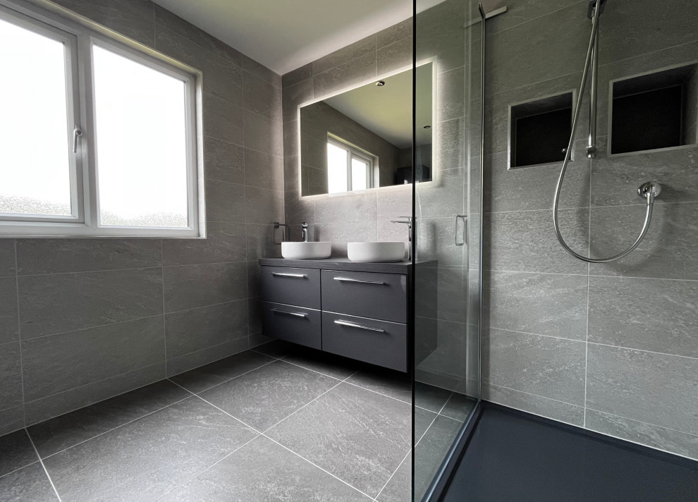 Ejemplo de cuarto de baño principal, doble y flotante minimalista de tamaño medio con armarios con paneles lisos, puertas de armario grises, ducha doble, baldosas y/o azulejos grises, suelo gris, ducha abierta y encimeras grises