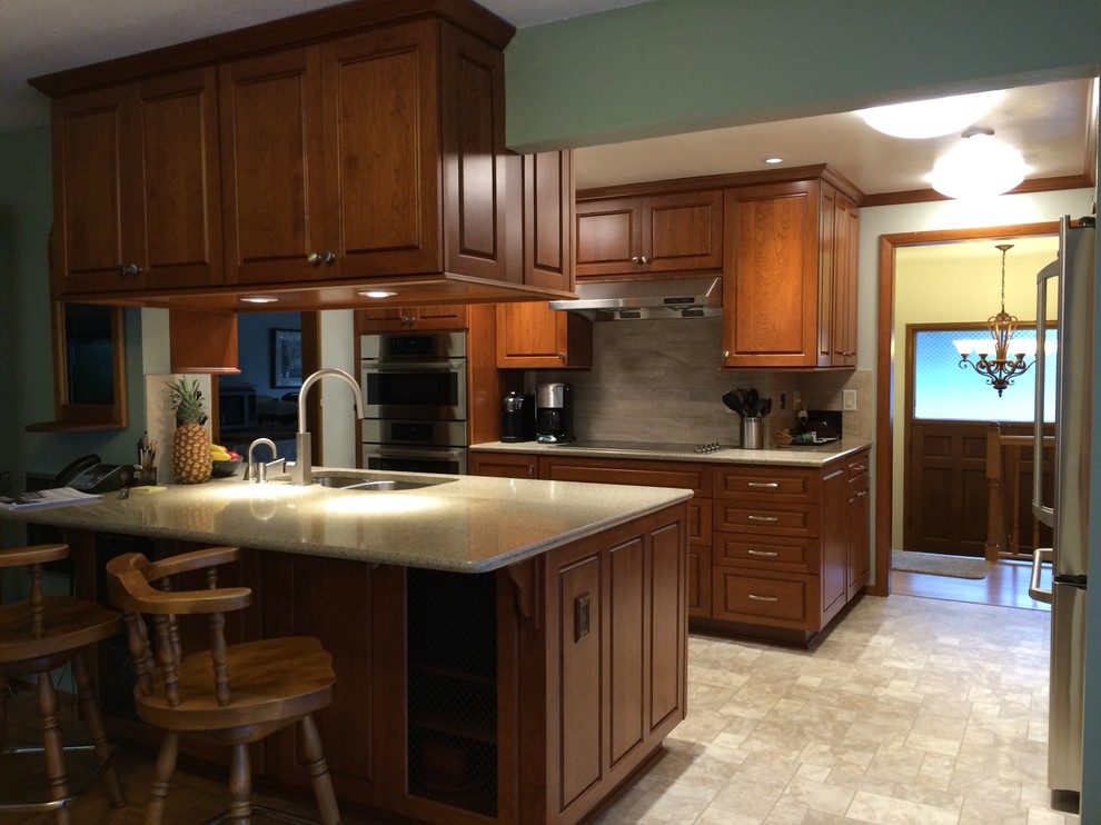Example of a mid-sized transitional linoleum floor kitchen design in Seattle with an undermount sink, raised-panel cabinets, medium tone wood cabinets, quartzite countertops, beige backsplash, ceramic backsplash and stainless steel appliances