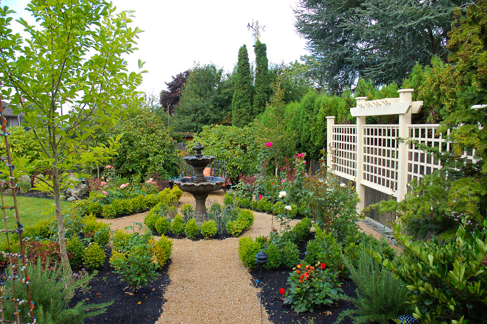 Photo of a mid-sized traditional backyard full sun formal garden in Seattle with a water feature and gravel.