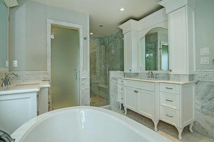Photo of a traditional bathroom in New York with recessed-panel cabinets, white cabinets, wood benchtops, white tile and wood-look tile.