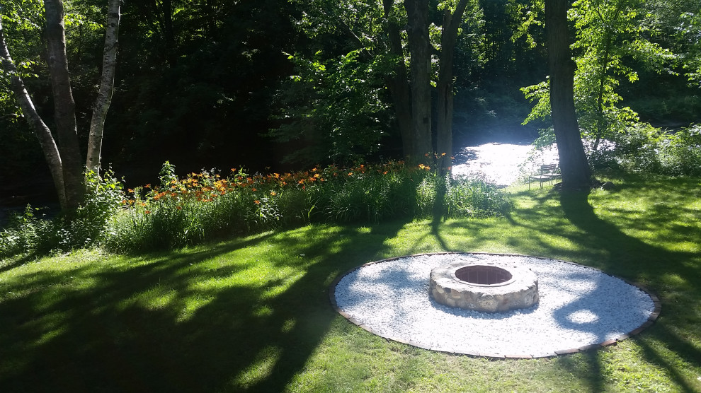 Small country backyard full sun garden in Boston with a fire feature and river rock for fall.