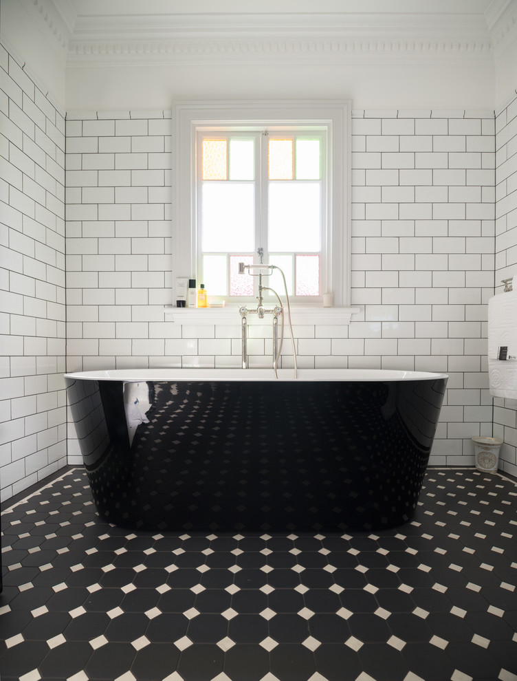 This is an example of a large contemporary master bathroom in Sydney with a freestanding tub, white tile, subway tile, white walls, porcelain floors, a pedestal sink and black floor.